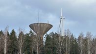 Puiden latvojen yläpuolelle kohoavat harmaa betoninen vesitorni ja tornia hiukan korkeampi tuulimylly.