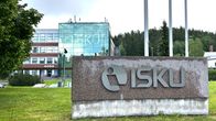 Lähikuvassa on graniittikivi, jossa tekstiä. Taustalla on korkea liikerakennus. 