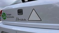 Valkoinen autokoulun auto, jossa perässä mustalla rajattu valkoinen opetuskolmio. 