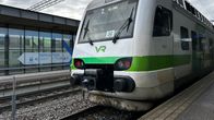 Lähikuvassa on valkoinen ja vihreä junan keula. Juna on parkissa asemalla. 