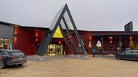 Metallinen korkea kehikko punaisen rakennuksen porttina.