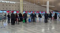 Photo shows people in a queue at Helsinki Airport.