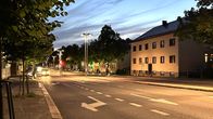 A car driving on the road, with street lamps on.