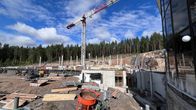 Rakennustyömaa iltapäivän auringossa: nosturi kohoaa taivasta vasten ja rakennusmateriaalit odottavat käyttöä.