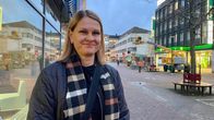Nainen seisoo ulkona kävelykadulla ympärillä näkyy liiketiloja ja apteekki.