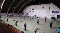 Eläkeläisten liikuntaryhmä kaarevakattoisessa liikuntahallissa.