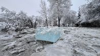 Talvinen maisema, jossa maa ja puut ovat lumen ja jään peittämänä. Etualalla näkyy suuri jääkuutio.