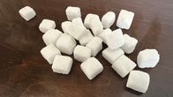 Small pile of sugar cube chunks on a brown table.