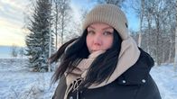 Outi oaltto seisoo talvikelillä ulkona talvivatteissa pipo päässä. Taustalla näkyy lumisia puita.
