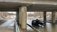 Sillan alla kulkevalla kadulla on paljon vettä ja kaksi autoa pysähtyneenä. Vesi ulottuu autojen rekisterikilpiin asti.
