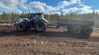 Traktori ja perävaunu työskentelevät turvesuolla kevätauringon paisteessa.