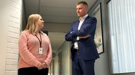 Kaksi henkilöä keskustelee toimistokäytävällä.