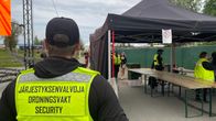 Järjestyksenvalvoja seisoo selin festivaalialueelle vievällä portilla.