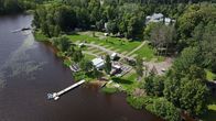 Ilmakuva leirintäalueesta veden äärellä, rannassa laituri ja useita rakennuksia sekä pysäköinti- ja nurmialueita.
