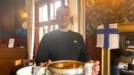 Kaljupäinen mies, Leijonien videovalmentaja Jukka Varmanen, seisoo ja pitää MM-pokaalia käsissään. 