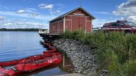 Kuvassa punainen rakennus, jonka seinässä lukee "öljyntorjuntavarasto". Etualalla on jokin punainen öljyntorjuntaväline.