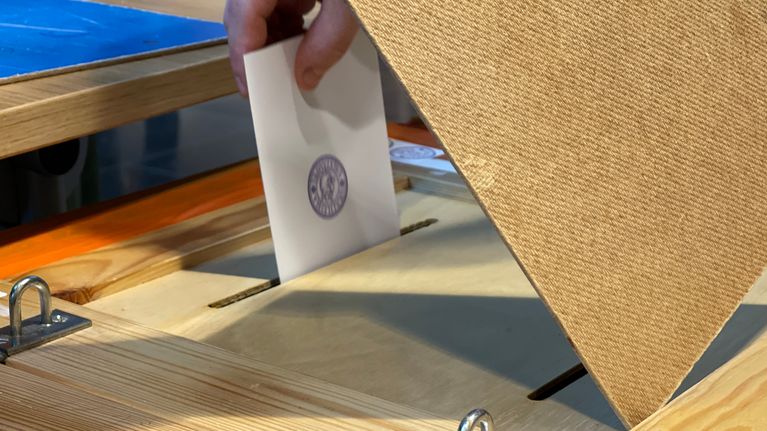 Vaaliuurnaan menevä äänestyslippu.