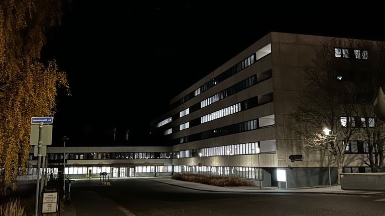 Lähikuvassa on suuri betonirakennus, jossa on monia kerroksia. Osassa ikkunoista on valo. 