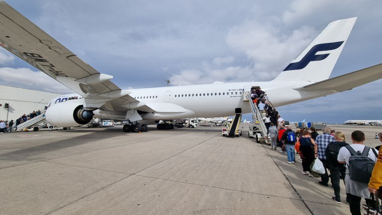 People lining up at the back end of a jet on the tarmac.