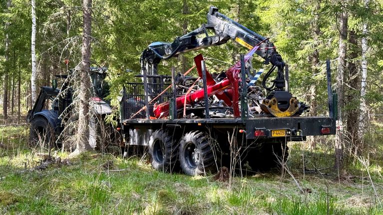 Traktori kuljettaa tuhoutuneen kopterini kappaleita metsäisessä ympäristössä.