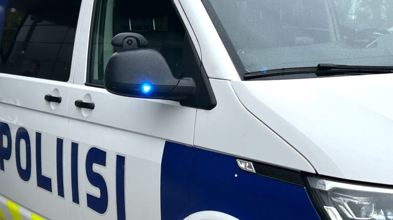 Lähikuvassa on sinivalkoinen pakettiauto, jonka kyljessä lukee sinisellä poliisi. 
