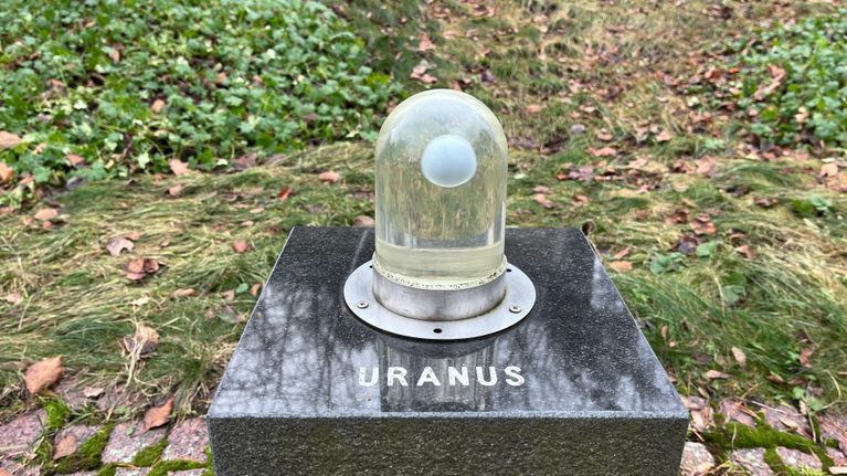 kuvassa on teos, jossa on kupu, jonka sisällä oleva pallo kuvaa Uranus-planeettaa.