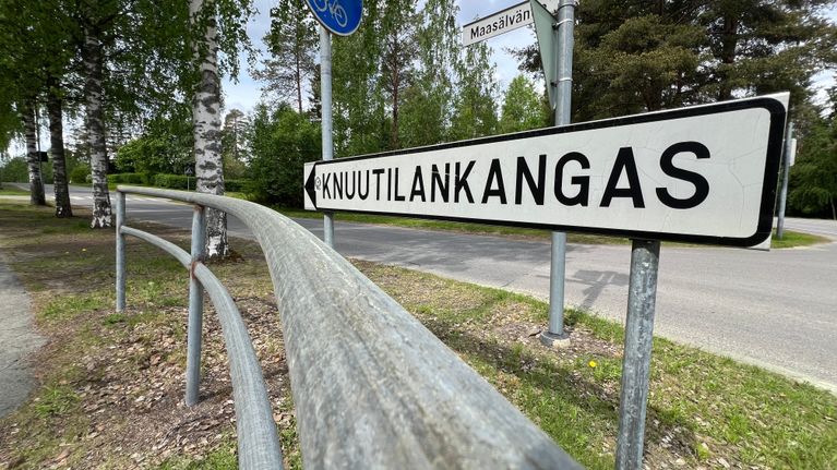 White road sign that reads "Knuutilankangas", with trees and small roads in the background.