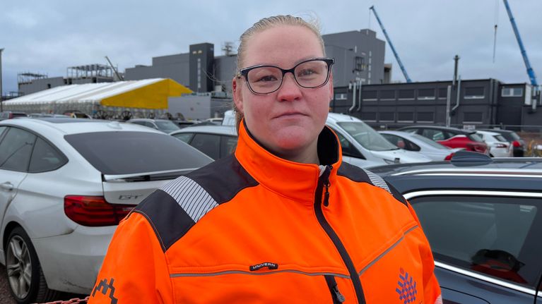 Nainen katsoo kameraan ja yllä hänellä on kirkkaan oranssinen takki.