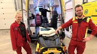 Ensihoitajat Emilia Leino ja Kristian Mäkinen seisovat ambulanssi paarien vieressä ja katsovat kameraan. Taustalla näkyy lähiesimies Valtteri Kankaanpää. 