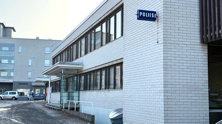 Kangasalan poliisiaseman valkoisen tiilirakennuksen sivu. Seinässä on sininen poliisikyltti.