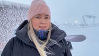 Talvivaatteisiin pukeutunut, laskettelurinteessä oleva vaaleatukkainen nainen katsoo suoraan kameraan.