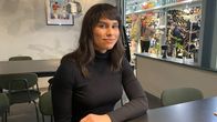 Film Tampereen ohjelmajohtaja Fanny Heinonen katsoo kameraan pöydän ääressä mustassa poolossa. 