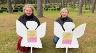 Kaksi henkilöä hautausmaalla enkelikuvioiden takana.