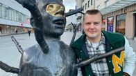 Kuvassa mies poseeraa patsaan vieressä.