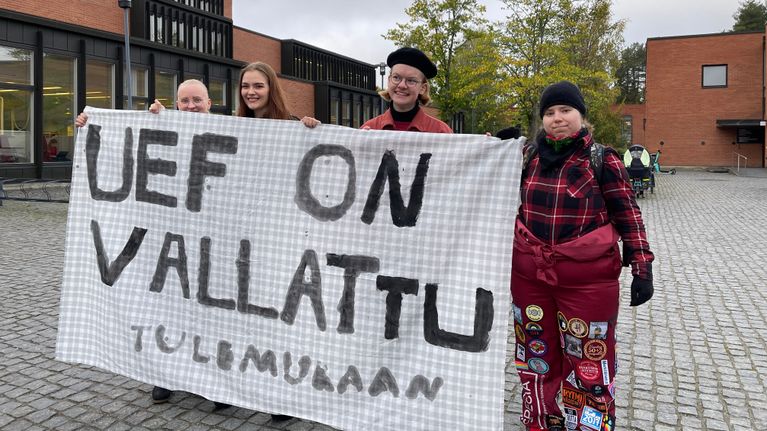 Neljällä nuorella opiskelijalla on käsissään mielenosoituslakana.