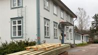 Ulkokuva Pyhtään kulttuuritalosta. Kulttuuritalon liepeillä lautapino.