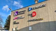 Kuvassa on teollisuusrakennuksen seinä, johon on kiinnitetty useita yrityslogoja. Logot kuuluvat seuraaville yrityksille: Immensa Biotech, Clingate, Synbio Powerlabs, Synbio Powerhouse, Eternal ja Nordiquan. Rakennus sijaitsee lumisessa ympäristössä, ja taivaalla on ripaus pilviä