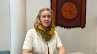 Nainen istuu ruokapöydän äärellä kahvikuppi kädessä. Henkilökuva. Marianne Mäki. 