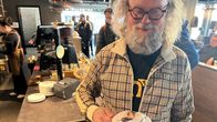 Mies nauttii kahvilassa kuumaa juomaa, jonka päällä on erikoiskoristelu.