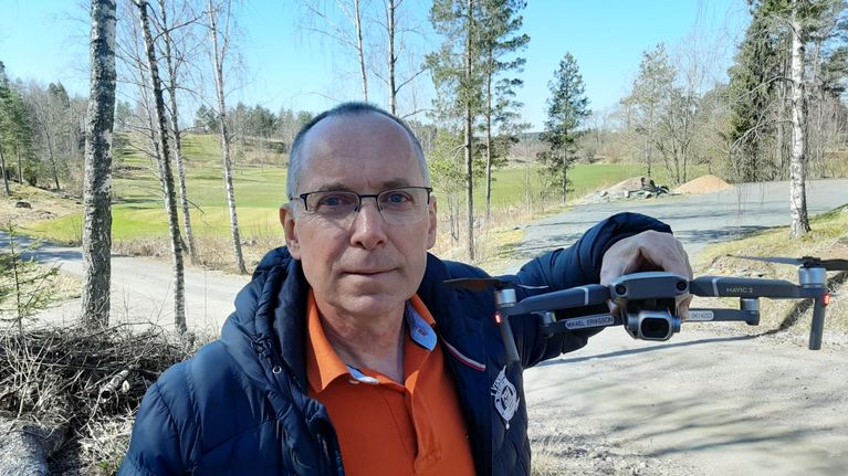 Micke Eriksson, en man med glasögon och kort hår, håller i en drönare.