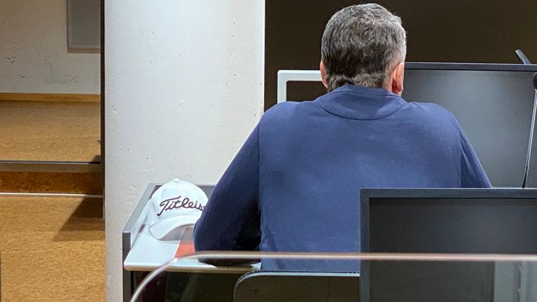Vastaaja oikeudenkäynnissä selin kameraan. 