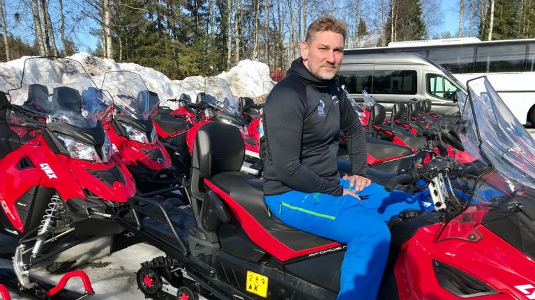 Rovaniemeläinen matkailuyrittäjä Sami Päivike safariyrityksensä moottorikelkkojen keskellä