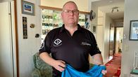 Mies katsoo kameraan ja esittelee Rion paralympialaispaitaa. 