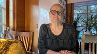 Henkilö istuu keittiössä pöydän ääressä kannettavan tietokoneen kanssa. Taustalla näkyy ikkunoista,  luonnonvaloa, sekä huonekasveja ja jääkaappi.