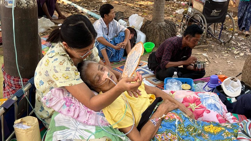 Nainen pitelee vanhusta sylissään maanjäristyksen jälkeen Myanmarissa. Vanhuksella happiviikset.