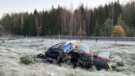 Tien varrella oleva pahoin vaurioitunut auto, jonka ympärillä on puna-keltaista nauhaa, taustalla metsä.