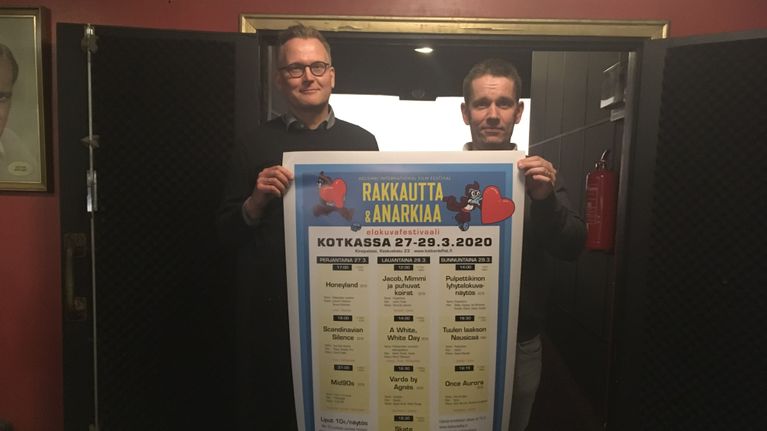 Kaksi miestä pitelevät festivaalijulistetta.