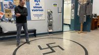 Kuvassa rehtori katsoo koulun lattiassa olevaa hakaristiä Iisalmen Lyseossa.