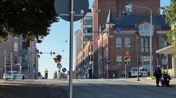 Vägkorsning avspärrad av polis, man ser flera polisbilar och en mc-polis.