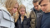 Mynämäen lukion abiturientit Ella Vuorinen(vas.), Emma Repo, Oliver Sainio ja Olavi Konttila katsovat kännykkää koulunsa parkkipaikalla. 